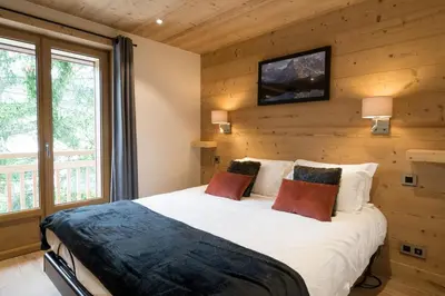 a bedroom with a bed in a wooden wall at Appartement JASIONE-MEGEVE in Megève