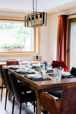 a dining room with a table with chairs and a chandelier at Appartement JASIONE-MEGEVE in Megève