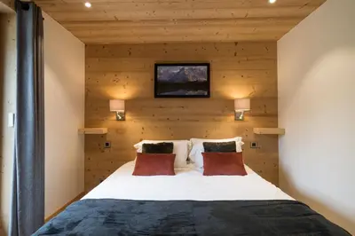 a bedroom with a bed with a wooden wall at Appartement JASIONE-MEGEVE in Megève