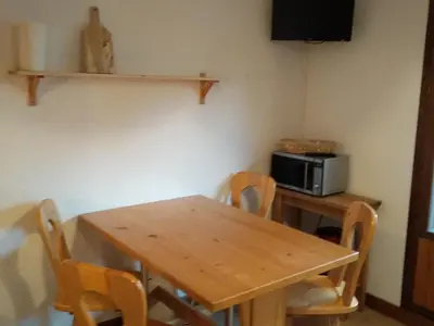 a dining room table with chairs and a microwave at Studio 4 pers Centre Station - Animaux OK - FR-1-836-65 in Arâches-la-Frasse