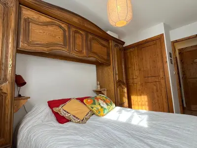 a bed with a wooden headboard and pillows on it at Charmant 3 Pièces Sud, Piscine & Animaux Acceptés - FR-1-629-155 in Samoëns