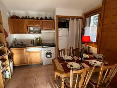 a kitchen with a table and chairs and a kitchen with a refrigerator at Charmant 3 Pièces Sud, Piscine & Animaux Acceptés - FR-1-629-155 in Samoëns
