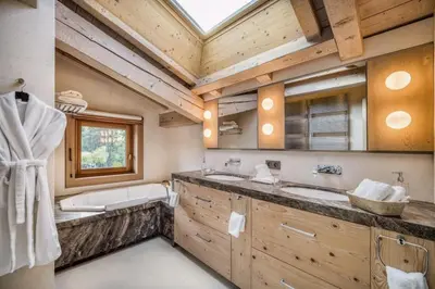 a bathroom with two sinks and a bath tub and a window at Chalet Le 34 Megève - Chalet dexception in Le Planellet