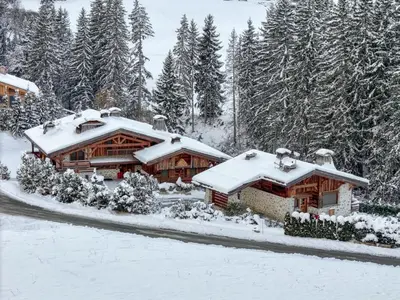 a house covered in snow in front of trees at Chalet Le 34 Megève - Chalet dexception in Le Planellet