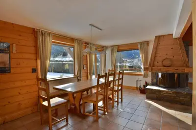 a dining room with a table and chairs and a fireplace at Chalet vallée de Chamonix, vue glaciers MontBlanc by ImmoConciergerie in Les Houches