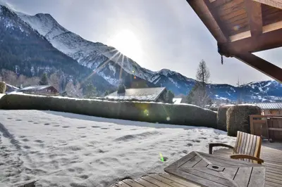 a snow covered patio with a table and a chair at Chalet vallée de Chamonix, vue glaciers MontBlanc by ImmoConciergerie in Les Houches