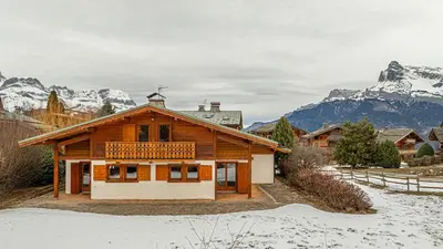 a wooden building with mountains in the background at White Chalet in Combloux