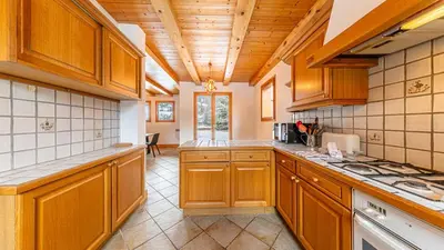 a large kitchen with wooden cabinets and a ceiling at White Chalet in Combloux
