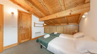 a bedroom with a large bed and wooden ceilings at White Chalet in Combloux