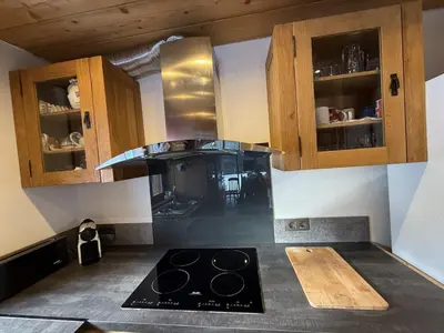 a kitchen with a stove and wooden cabinets at Chalet du Gouter in Les Houches