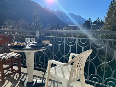 a table and chairs on a balcony with a view of a mountain at Bel appartement avec vue exceptionnelle in Chamonix-Mont-Blanc
