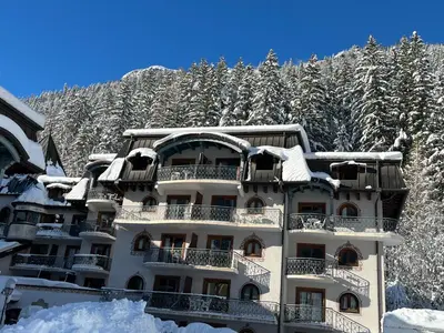 a building covered in snow in front of a mountain at Bel appartement avec vue exceptionnelle in Chamonix-Mont-Blanc