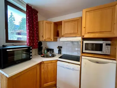 a kitchen with wooden cabinets and a sink and a microwave at La grande cordée in Combloux