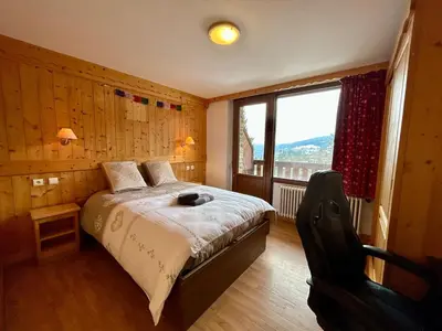 a bedroom with a bed and a large window at La grande cordée in Combloux