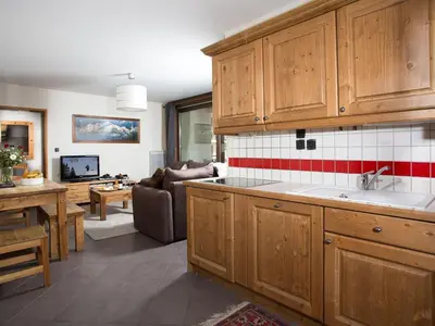 a kitchen with wooden cabinets and a living room at Apartment Le Paradis Ski Wohnung by Interhome in Chamonix-Mont-Blanc