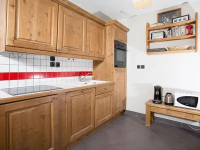 a kitchen with wooden cabinets and red and white tiles at Apartment Le Paradis Ski Wohnung by Interhome in Chamonix-Mont-Blanc