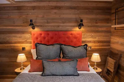 a bedroom with a bed with an orange headboard and two lamps at Chalet Khione in Chamonix-Mont-Blanc