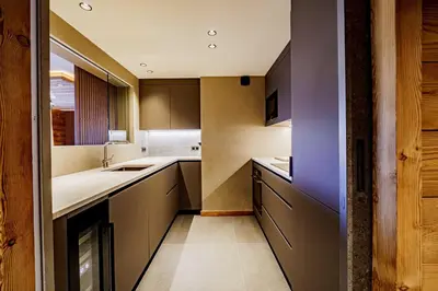a kitchen with brown cabinets and a purple wall at Modern Alpine Chalet a c 4BR 7P - Megève in Megève