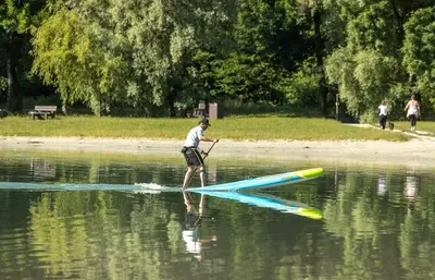 a man is on a paddle board in the water at Camping Les Iles in Passy