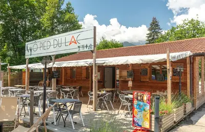 a sign in front of a restaurant with tables and chairs at Camping Les Iles in Passy