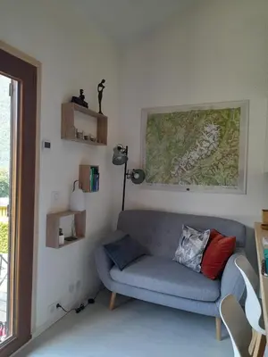 a living room with a blue couch and a window at Chalet mitoyen au calme - rez-de-jardin - parking in Les Houches
