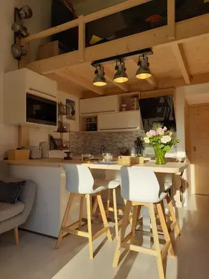a kitchen with a table and chairs and a counter at Chalet mitoyen au calme - rez-de-jardin - parking in Les Houches