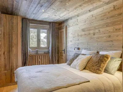 a bed in a room with a wooden wall at Appartement 3 Chambres, Terrasse Sud/Ouest, Parking - Megève - FR-1-453-331 in Megève