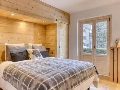 a bedroom with a bed with a wooden wall at Appartement 3 Chambres, Terrasse Sud/Ouest, Parking - Megève - FR-1-453-331 in Megève