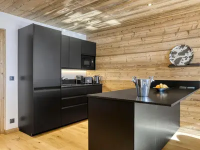 a kitchen with black appliances and a wooden wall at Appartement 3 Chambres, Terrasse Sud/Ouest, Parking - Megève - FR-1-453-331 in Megève