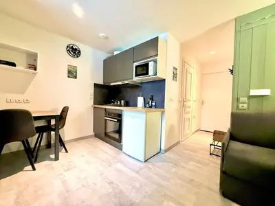 a kitchen and dining room with a table and a counter at Studio Cosy avec balcon in Combloux