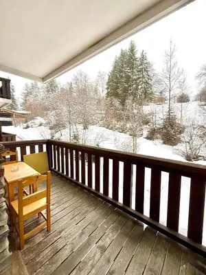 a balcony with a table and a view of a snow covered field at Studio Cosy avec balcon in Combloux