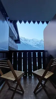 two wooden chairs on a balcony with a view of mountains at Appt 4 pers Chamonix in Chamonix-Mont-Blanc