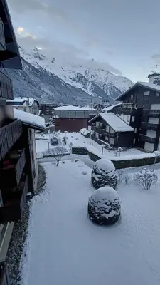 a yard covered in snow with mountains in the background at Appt 4 pers Chamonix in Chamonix-Mont-Blanc