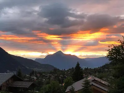 a sunset over a city with a mountain at Appartement dans Chalet aux pieds des pistes in Arâches-la-Frasse