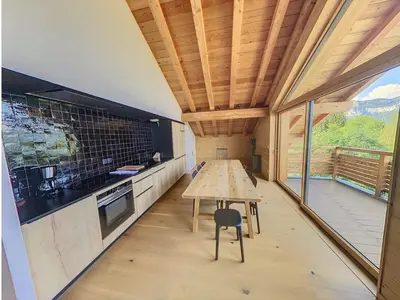 a kitchen with a wooden table and a large window at Appartement dans Chalet aux pieds des pistes in Arâches-la-Frasse