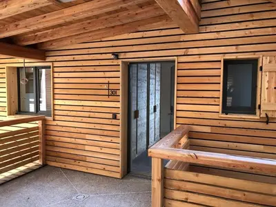 a wooden building with a bench in front of a door at Appartement dans Chalet aux pieds des pistes in Arâches-la-Frasse
