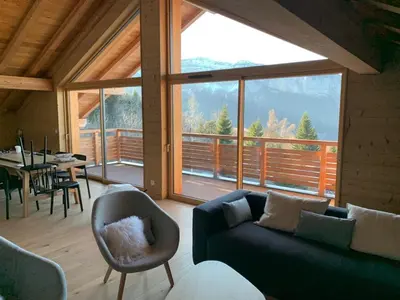 a living room with a couch and a large window at Appartement dans Chalet aux pieds des pistes in Arâches-la-Frasse