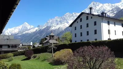 a large white building with mountains in the background at T2 pour 6 pers Les Houches in Les Houches