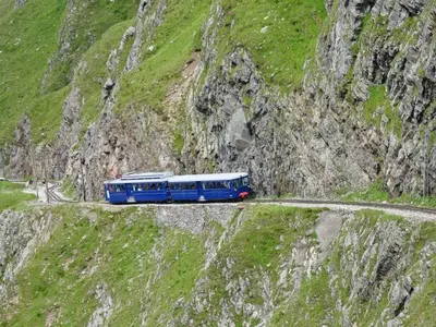 a blue train traveling on a mountain road at T2 pour 6 pers Les Houches in Les Houches