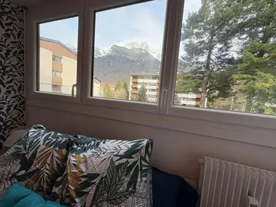 a living room with a couch and two windows at Modern Alpine Gem Flat with mountain views in Sallanches