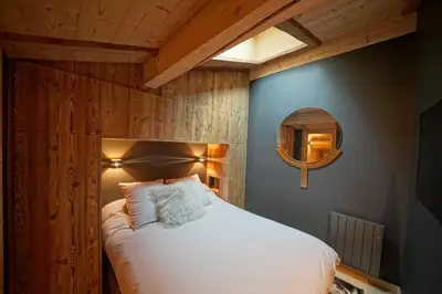 a bedroom with a white bed with a wooden wall at Warm Alpine apartment 2BR 5P - Megeve in Megève