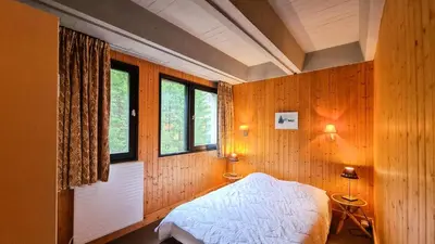 a bedroom with wooden walls and a bed and windows at Résidence Aldebaran - Appartement spacieux avec casier à ski · Ski aux pieds · Balcon MAE-4994 in Magland