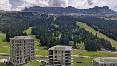 a view of a building with mountains in the background at Résidence Aldebaran - Appartement spacieux · Départ et retour ski aux pieds · Balcon MAE-5024 in Magland