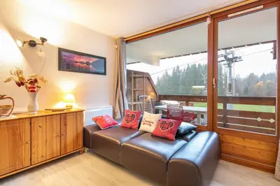 a living room with a leather couch and a large window at Gélinotte 23 - Station de ski à pied in Morillon