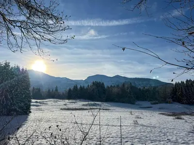 a snow covered field with the sun in the background at Escapade aux Carroz in Arâches-la-Frasse