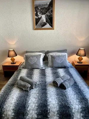 a bedroom with a bed with two lamps and towels on it at Superbe T3- Vue Mont-Blanc- Au pied du Brévent- Chamonix in Chamonix-Mont-Blanc