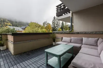 a patio with a couch and a table on a balcony at Apartment with terrace Gentianes 1 Centre Chamonix by Aiguille du Midi in Chamonix-Mont-Blanc