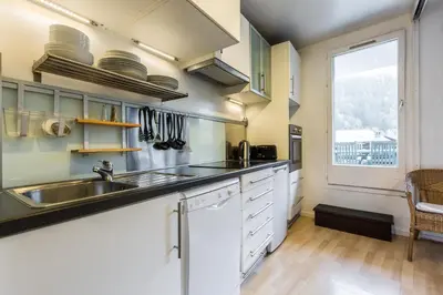 a kitchen with white cabinets and a sink and a window at Apartment with terrace Gentianes 1 Centre Chamonix by Aiguille du Midi in Chamonix-Mont-Blanc