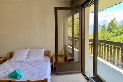 a bedroom with a bed and a balcony with a view at Apartment near the slopes in Combloux in Combloux
