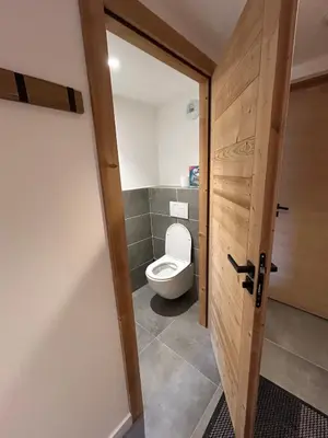 a bathroom with a toilet and a wooden door at Appartement standing 3 chambres, Luxury 3-bedroom apartment 75m2 in Arâches-la-Frasse